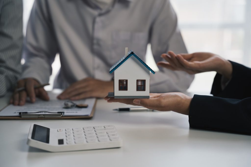 real estate agent or salesman holds a house model to describe the details of the house to customer